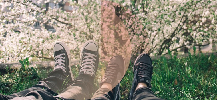 Ein Paar genießt den Frühling und liegt in der Wiese, zu sehen sind nur die Füße