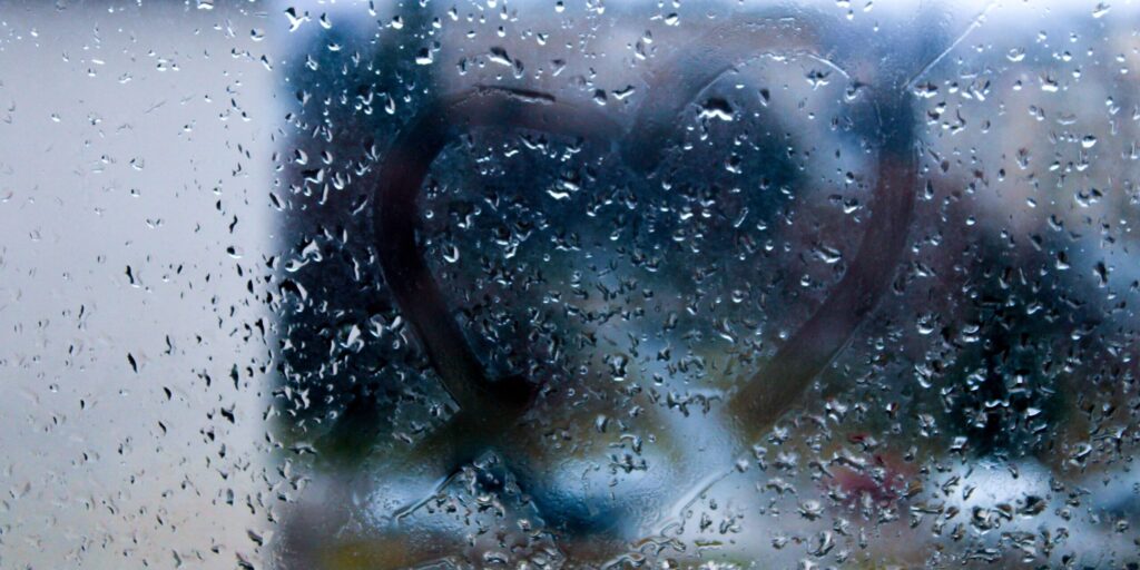 Herzform auf nassem Glas vom Regen, mit dem Finger gezeichnet für romantischen Hintergrund