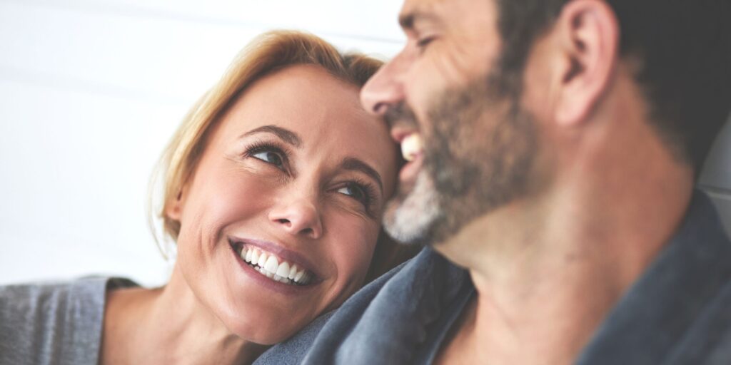 Ein Paar entspannt sich zu Hause im Bett. Ein glücklicher reifer Mann und eine verliebte Frau sitzen morgens im Schlafzimmer und teilen einen romantischen Moment