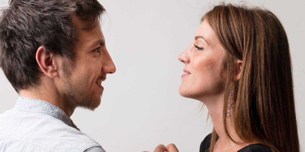 Ein Mann und eine Frau stehen sich in spielerischem Trotz gegenüber und fordern sich gegenseitig zu einem Armdrücken heraus. Sie symbolisieren Mann und Frau, sowohl als Freunde als auch als Liebhaber und Rivalen, und bewahren dabei ein Gefühl von Stolz und Spaß