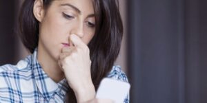 Eine Frau mittleren alters schaut traurig auf ihr Handy