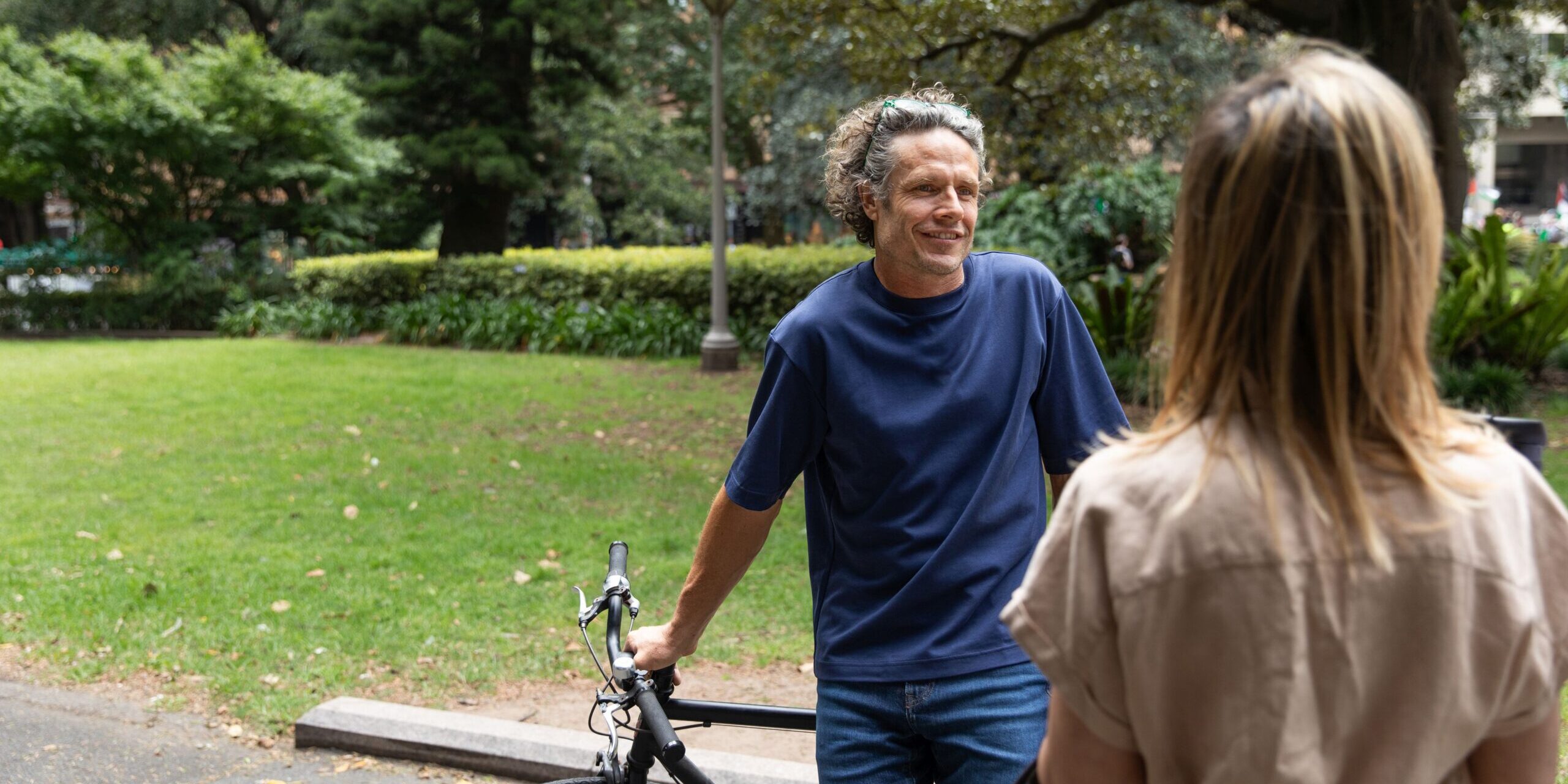 Frauund Mann in der Natur im Gespräch, er hält sein Fahrrad.