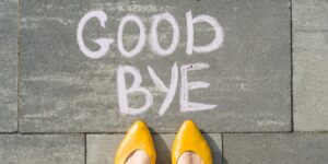 Weibliche Füße mit Text zum Abschied auf Asphalt geschrieben.