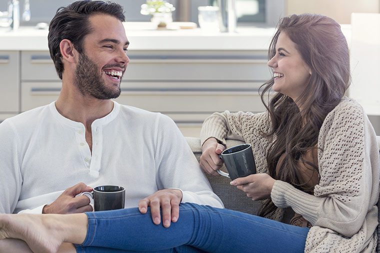 Pärchen sitzt gemeinsam und glücklich auf dem Sofa und trinken Kaffee