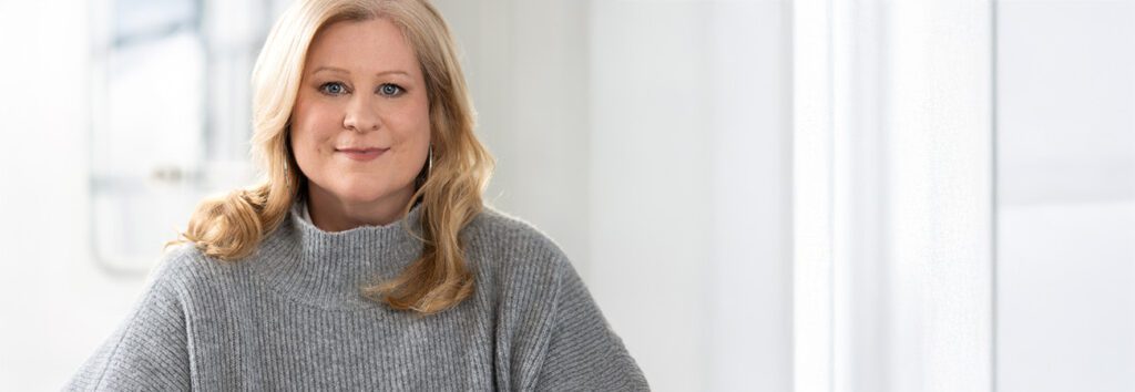 Foto von Silke Setzkorn vor hellgrauem Hintergrund.